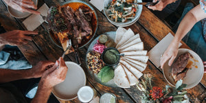 overhead of black angus beef shin and other side dishes with people sat around preparing to eat